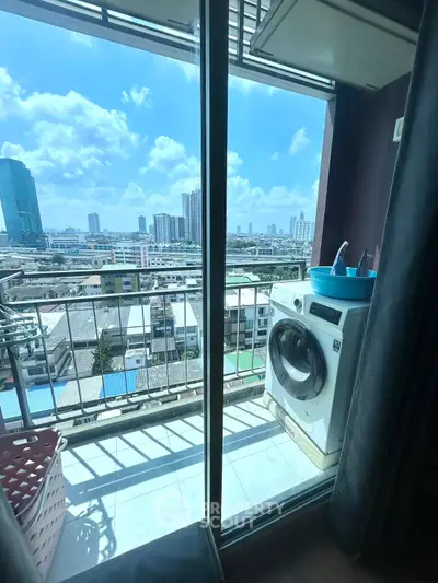 Stunning city view from a high-rise balcony with washing machine and bright blue sky.