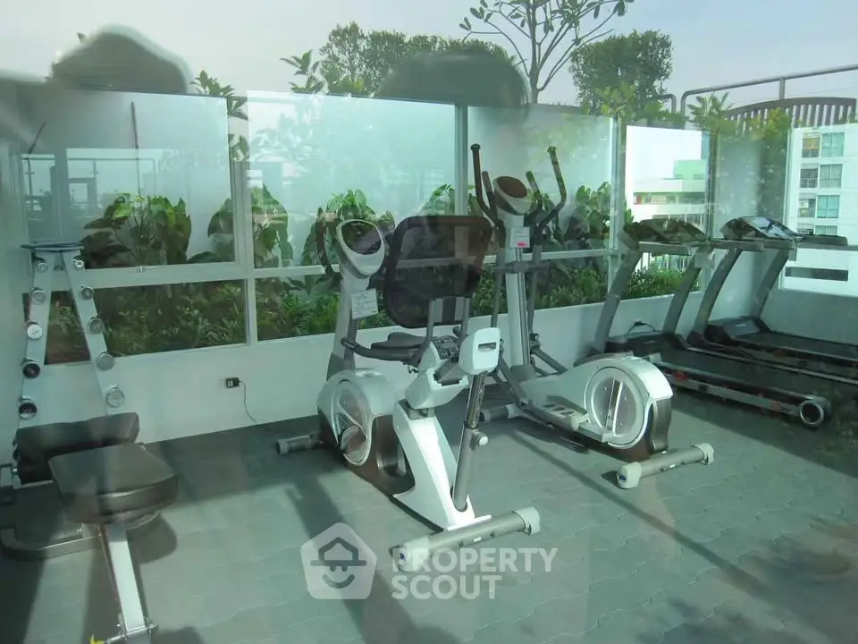 Modern gym with exercise equipment and greenery view in a residential building.