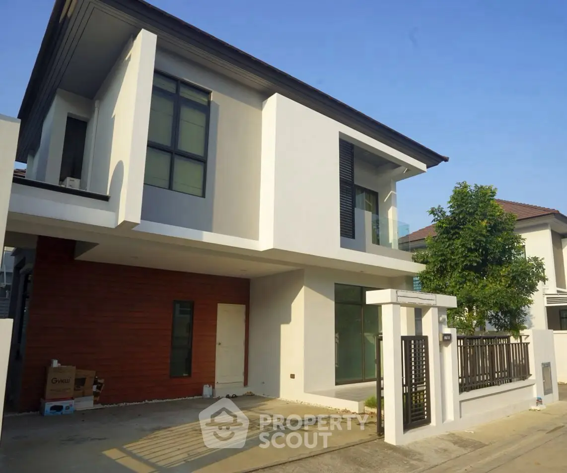 Modern two-story house with sleek design and spacious driveway in a suburban neighborhood.