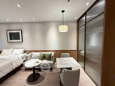 Modern studio apartment with cozy bed, stylish seating area, and elegant lighting.