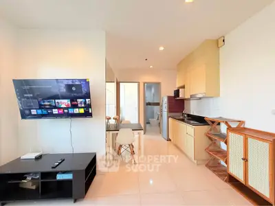Modern open-plan living room and kitchen with wall-mounted TV and stylish furniture.