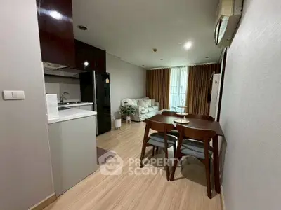 Modern open-layout living room with dining area and kitchen, featuring sleek furniture and natural lighting.