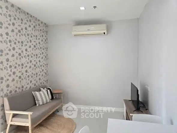 Modern living room with stylish decor and air conditioning, featuring a cozy sofa and flat-screen TV.