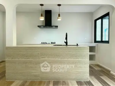 Modern kitchen with open layout and sleek design featuring gas stove and stylish lighting.