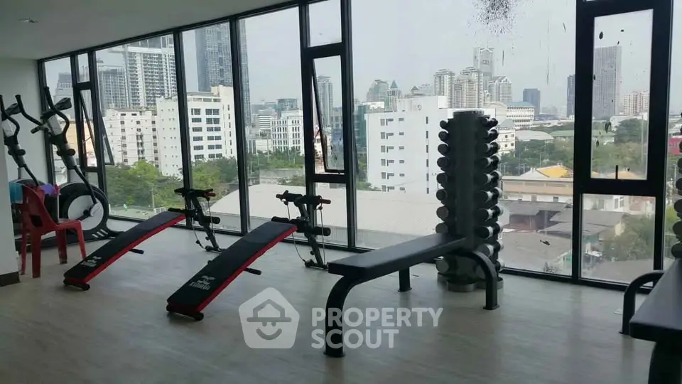 Modern gym with city view, featuring exercise equipment and large windows for natural light.