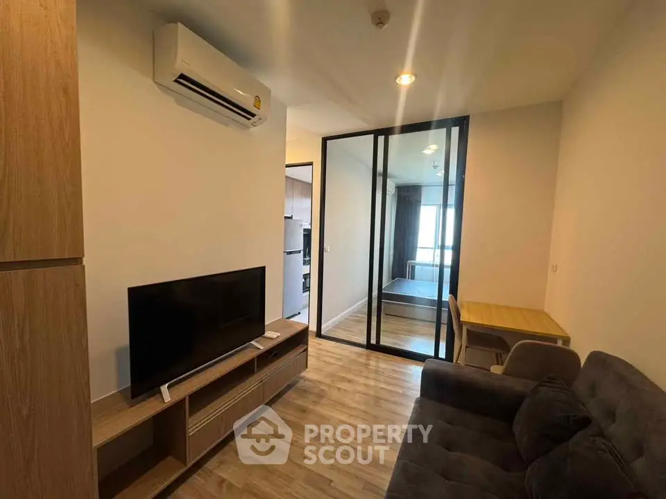 Modern living room with sleek design and glass partition leading to bedroom