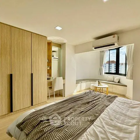 Spacious bedroom with modern decor, large window, and built-in wardrobe in a stylish apartment.