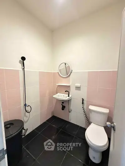 Compact bathroom with modern fixtures and pink tile accents, featuring a wall-mounted sink and toilet.