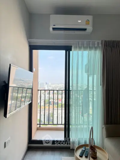 Modern living room with balcony and city view, featuring wall-mounted TV and air conditioning.