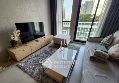 Modern living room with large TV, stylish furniture, and city view through floor-to-ceiling windows.