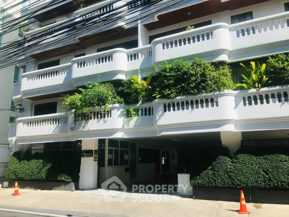 Charming residential building with lush greenery and spacious balconies in a vibrant neighborhood.