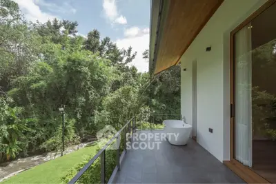 Luxurious balcony with freestanding bathtub and lush green view, perfect for relaxation and nature lovers.