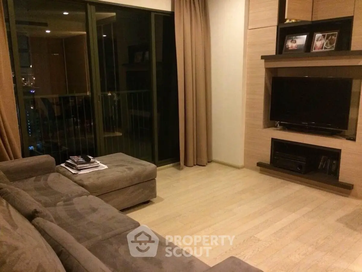 Cozy living room with modern decor and balcony access, featuring a plush sofa and entertainment center.