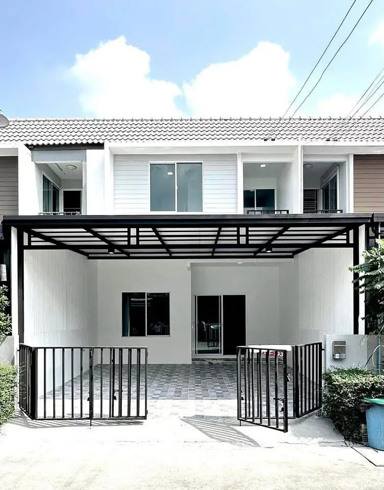 Modern townhouse exterior with gated entrance and covered parking area