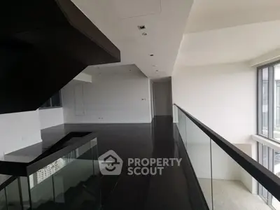 Spacious modern interior with sleek dark flooring and glass railing, offering a contemporary open layout.
