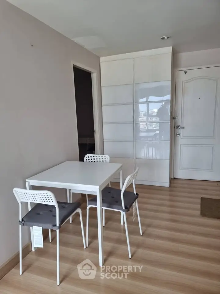 Modern dining area with sleek white table and chairs on wooden flooring, perfect for cozy meals.