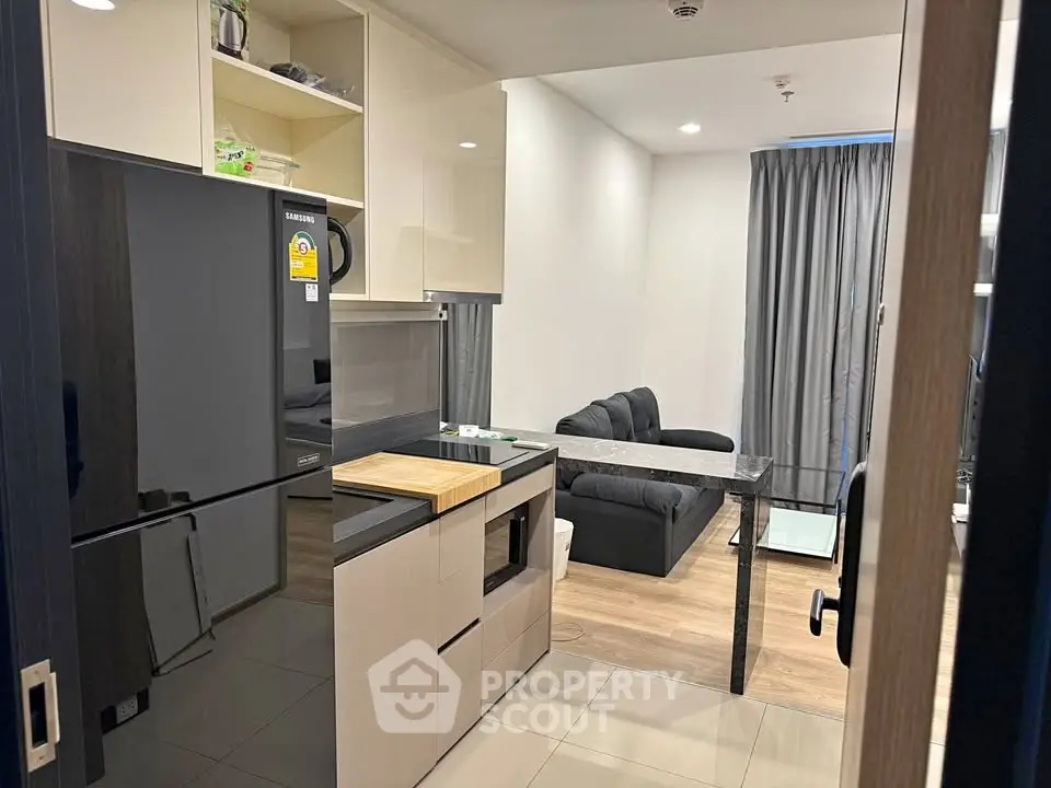 Modern open-layout kitchen and living room with sleek appliances and cozy seating area.