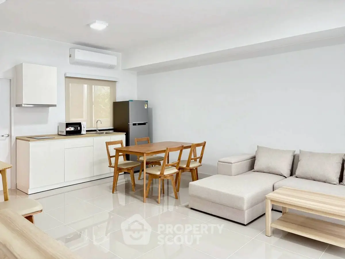 Modern open-plan living room with sleek kitchen and cozy dining area, perfect for contemporary living.