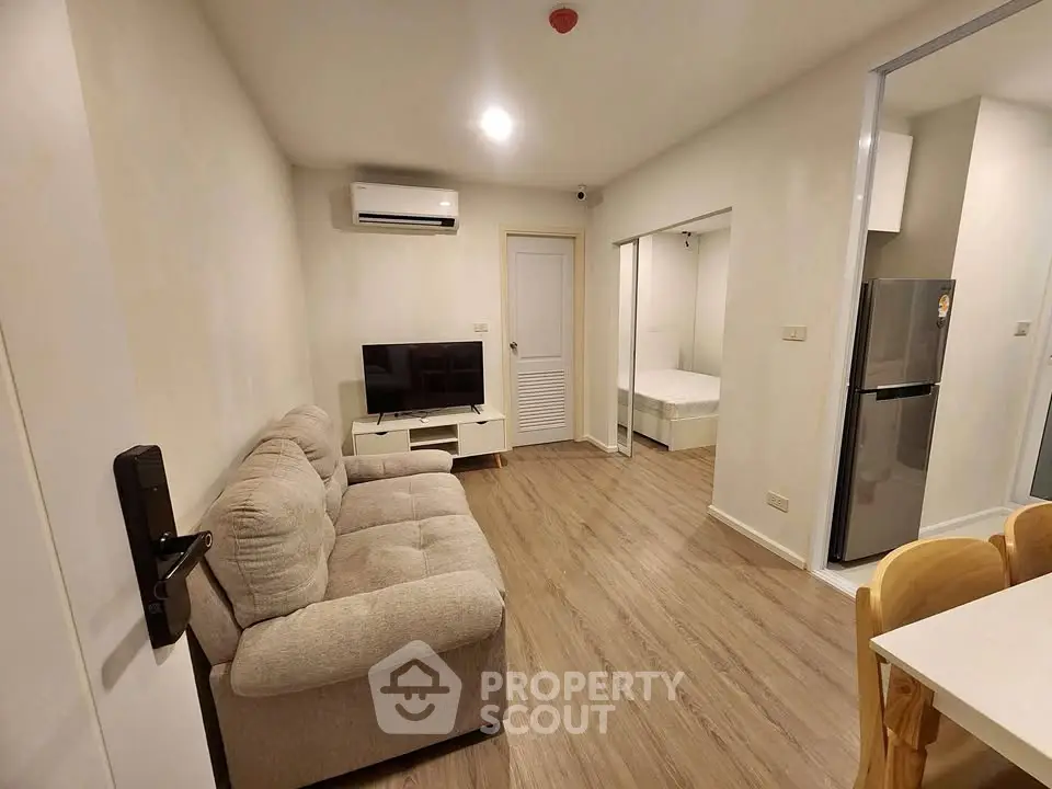 Modern apartment interior with cozy living room and kitchen area, featuring sleek furniture and wooden flooring.
