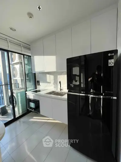 Modern kitchen with sleek black fridge and large windows offering city views.