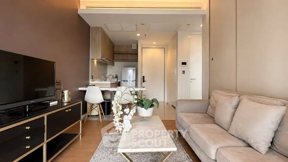 Modern living room with cozy sofa, sleek TV stand, and stylish open kitchen in a chic apartment.