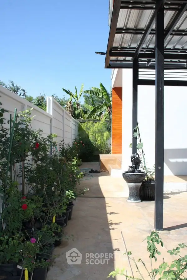 Charming garden patio with potted plants and modern pergola, perfect for outdoor relaxation.
