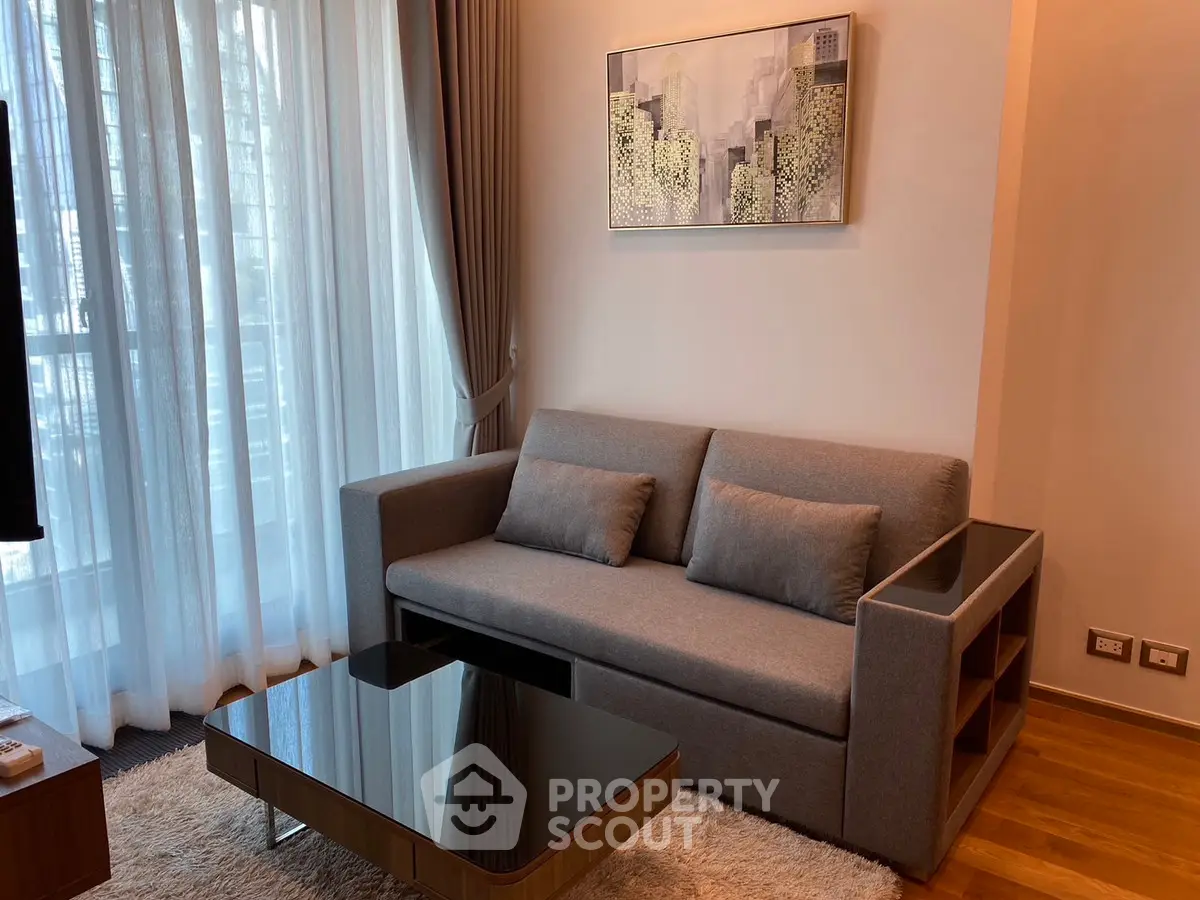 Modern living room with sleek gray sofa and stylish coffee table, featuring floor-to-ceiling windows.