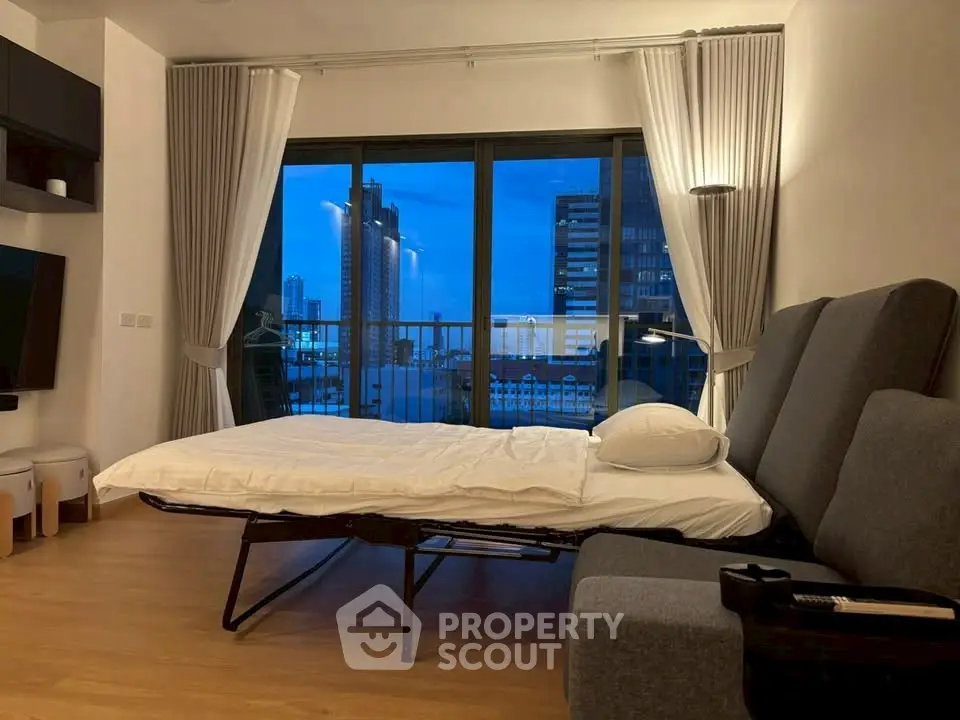 Modern living room with sofa bed and city view balcony at dusk