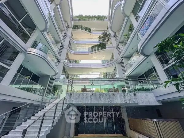 Modern multi-story building with lush greenery and glass balconies.