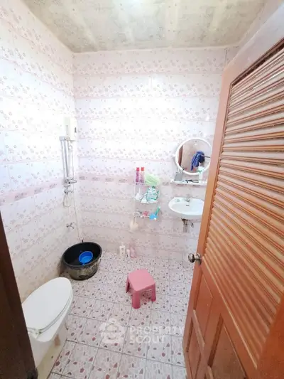 Cozy bathroom with floral tiles and essential amenities.
