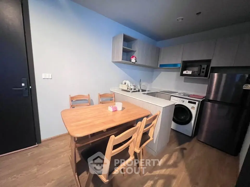 Modern kitchen with dining area, featuring sleek appliances and wooden furniture, perfect for cozy meals.