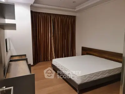 Spacious bedroom with wooden flooring and large window with brown curtains.