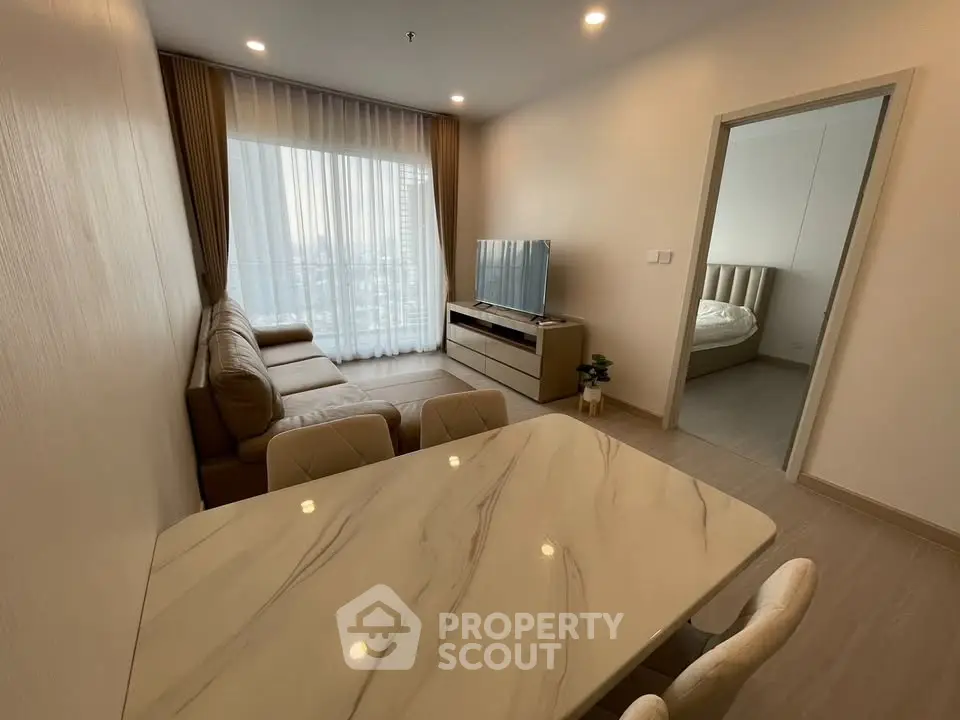 Modern living room with elegant furniture and natural light, featuring a cozy sofa and a sleek TV setup.