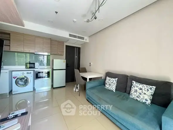 Modern living room with compact kitchen, featuring washing machine and cozy seating area.