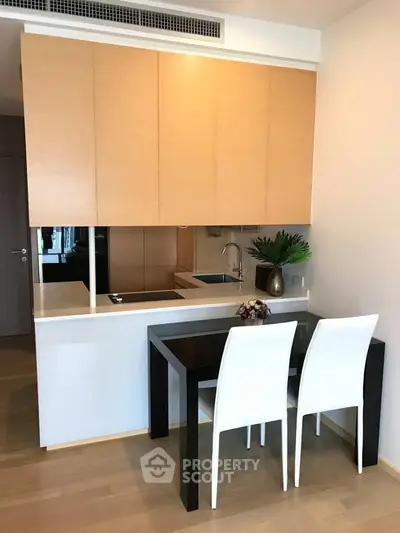 Modern compact kitchen with sleek cabinetry and dining area in stylish apartment
