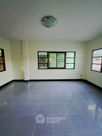 Spacious empty room with large windows and tiled flooring, perfect for customization.