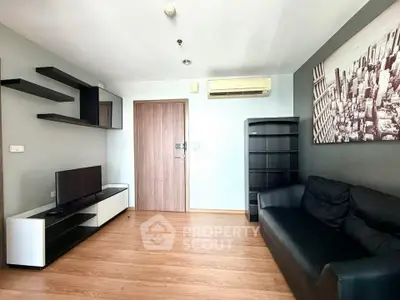 Modern living room with sleek furniture and wall art, featuring a cozy black sofa and wooden flooring.