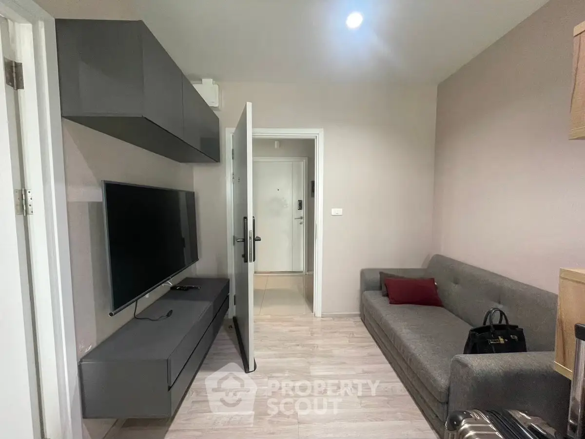 Modern living room with sleek TV setup and cozy sofa in stylish apartment.