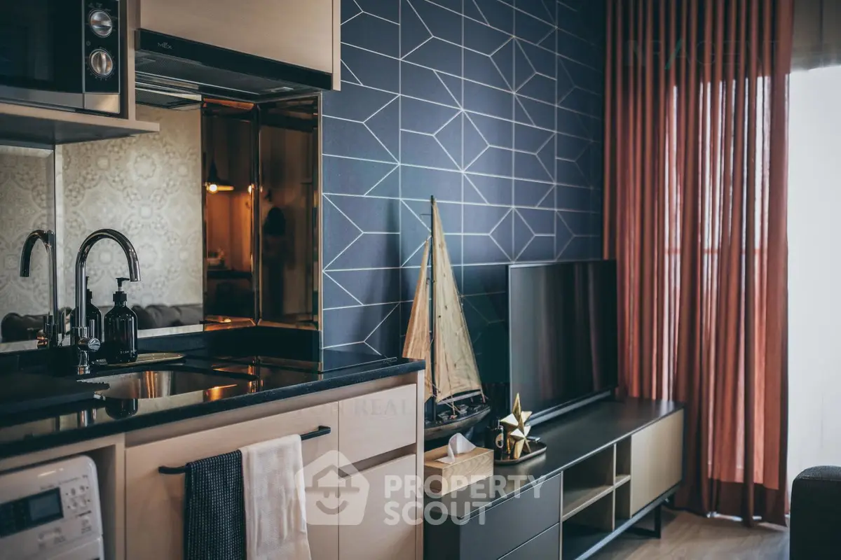 Stylish modern living room with geometric accent wall and sleek kitchen area.