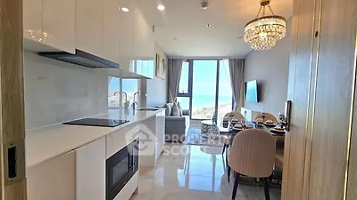 Luxurious open-layout kitchen and living room with ocean view and elegant chandelier.