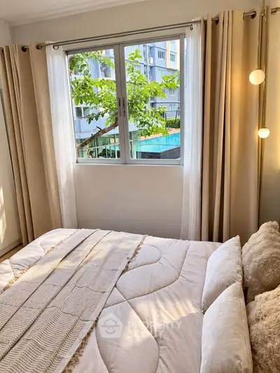 Cozy bedroom with large window and elegant curtains, offering a serene view of greenery outside.
