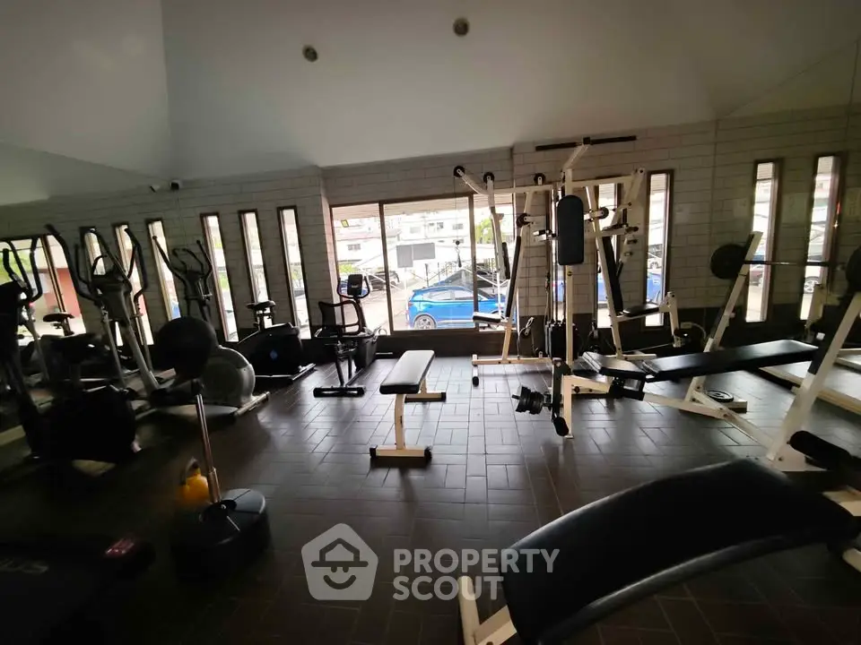 Spacious gym with modern equipment and large windows in residential building.