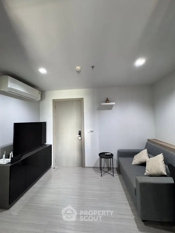 Modern living room with sleek furniture and minimalist design, featuring a comfortable sofa and wall-mounted TV.