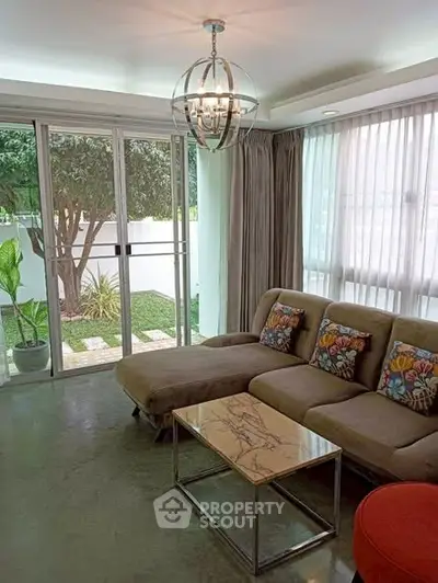 Stylish living room with modern decor and garden view, featuring a cozy sectional sofa and elegant lighting.