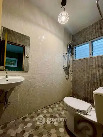 Modern bathroom with stylish tiles and compact design, featuring a sleek sink and toilet.