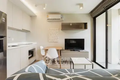 Modern living room with open kitchen and balcony access, featuring sleek furniture and natural light.