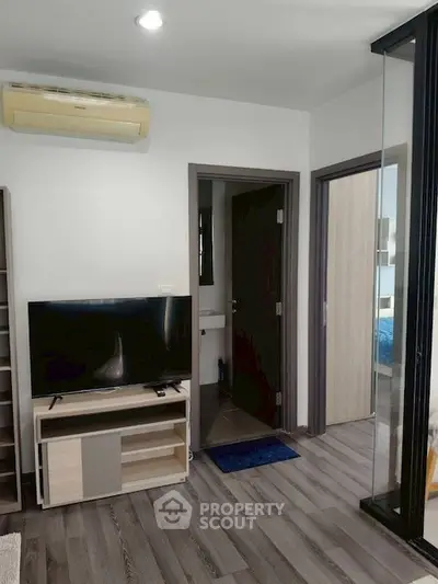 Modern living room with TV and air conditioning, featuring sleek flooring and open layout.