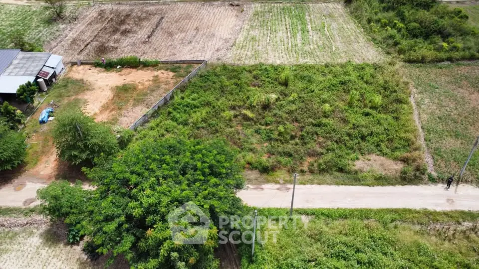 Aerial view of expansive green land plot ideal for development, featuring lush vegetation and clear access road.