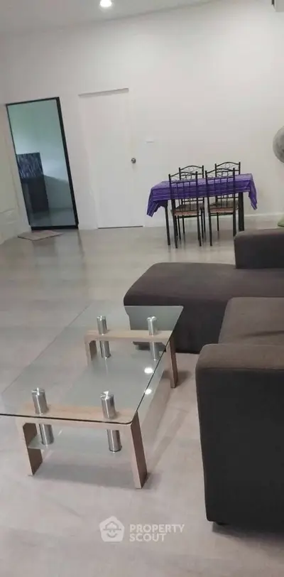 Modern living room with glass coffee table and dining area