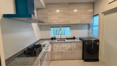 Modern kitchen with sleek cabinets, gas stove, and washing machine